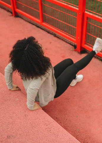 Athlete stretching on a track by a red fence